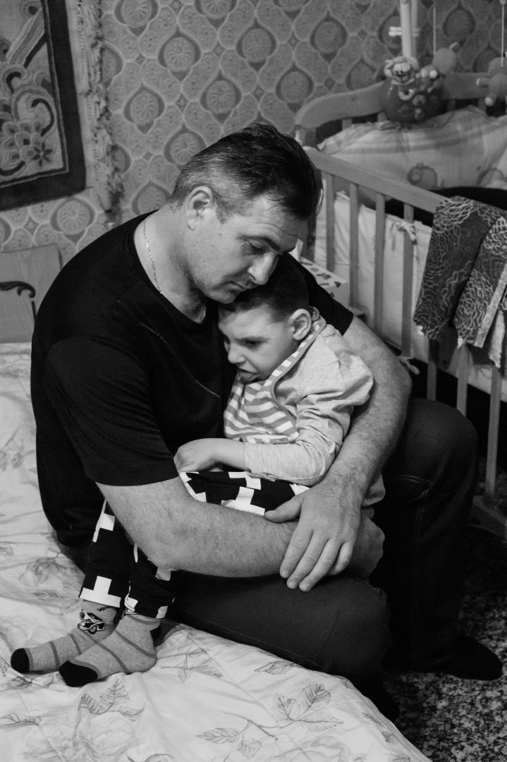 Arik Shraga. Humanitarian Photography. Danya and his father Danya suffers from microcephaly. He lives in one tiny room with his mother and father. His father used to be a police instructor until recently he was selected for redundancy and fired. Without assistance of the Jewish charity the family would literally have no bread on their table, not to mention expensive medicines needed daily to support Danya’s fragile body.
In this incredibly challenging situation Danya’s parents find their life fulfilled: they love Danya and dedicate themselves to him.