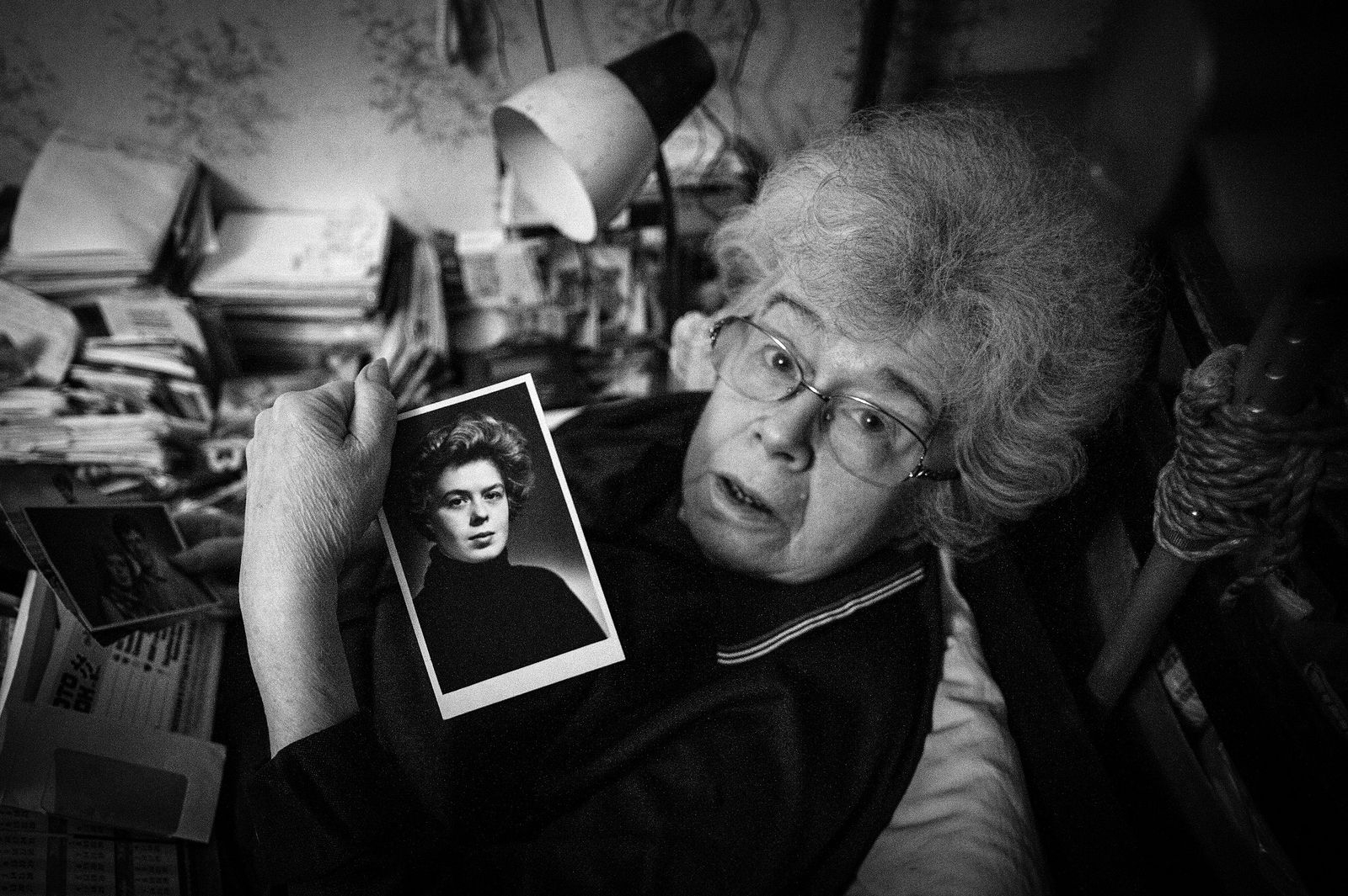 Arik Shraga. Russia. Ural region. Yekaterinburg. Inna Inna is holding her own portrait which dates back to her last years of normal healthy life. She laughs at me when I ask if she can really walk out and tells a horrible story of what’s thought of as a malpractice. When she was giving a birth in 1970 a midwife broke her pubic articulation. A bracket was installed but after 35 years it became completely loose.